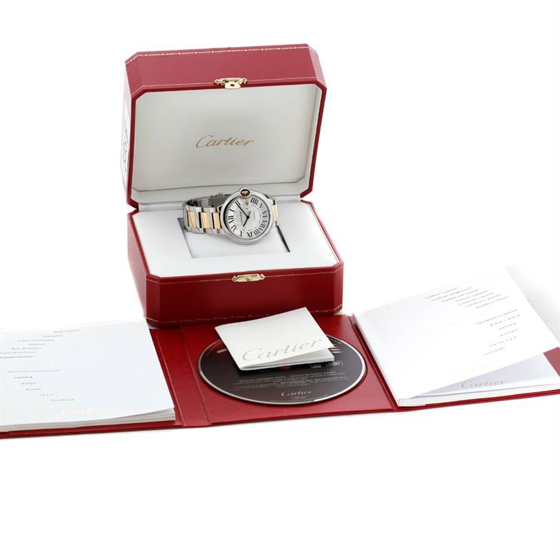 The image shows a Cartier Ballon Bleu W69009Z3 Men
s Stainless Steel Silver Dial W69009Z3 Men
s Stainless Steel Silver Dial watch in an open red box with accompanying booklets and a CD.