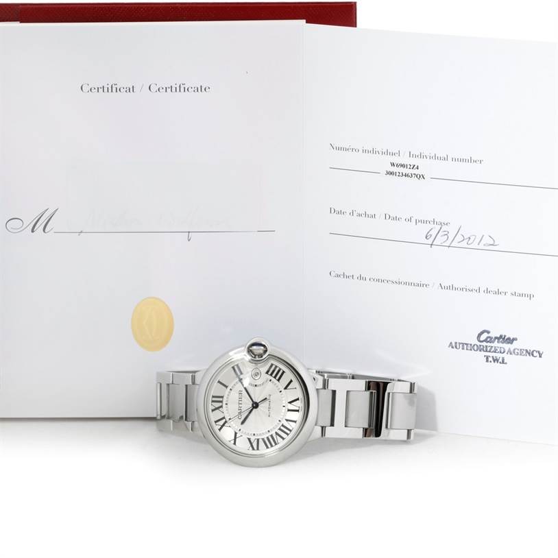 The image shows a Cartier Ballon Bleu W69012Z4 Men's Stainless Steel Silver Dial W69012Z4 Men's Stainless Steel Silver Dial watch positioned in front of its certificates and a red box.