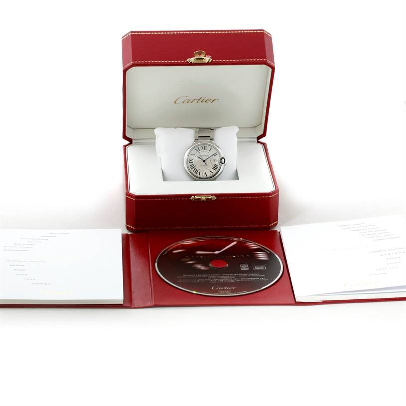 The image shows a Cartier Ballon Bleu W69012Z4 Men's Stainless Steel Silver Dial W69012Z4 Men's Stainless Steel Silver Dial watch in an open red box, accompanied by a user manual and a CD placed in front.