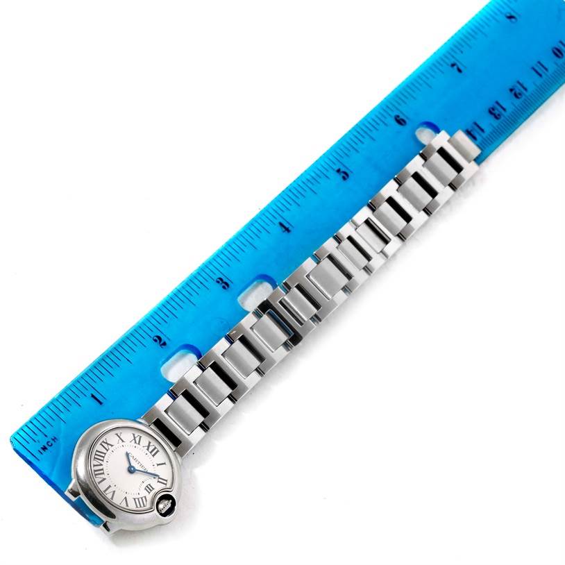The image shows the side view of the Ballon Bleu de Cartier watch, focusing on part of the bracelet alongside a blue ruler.