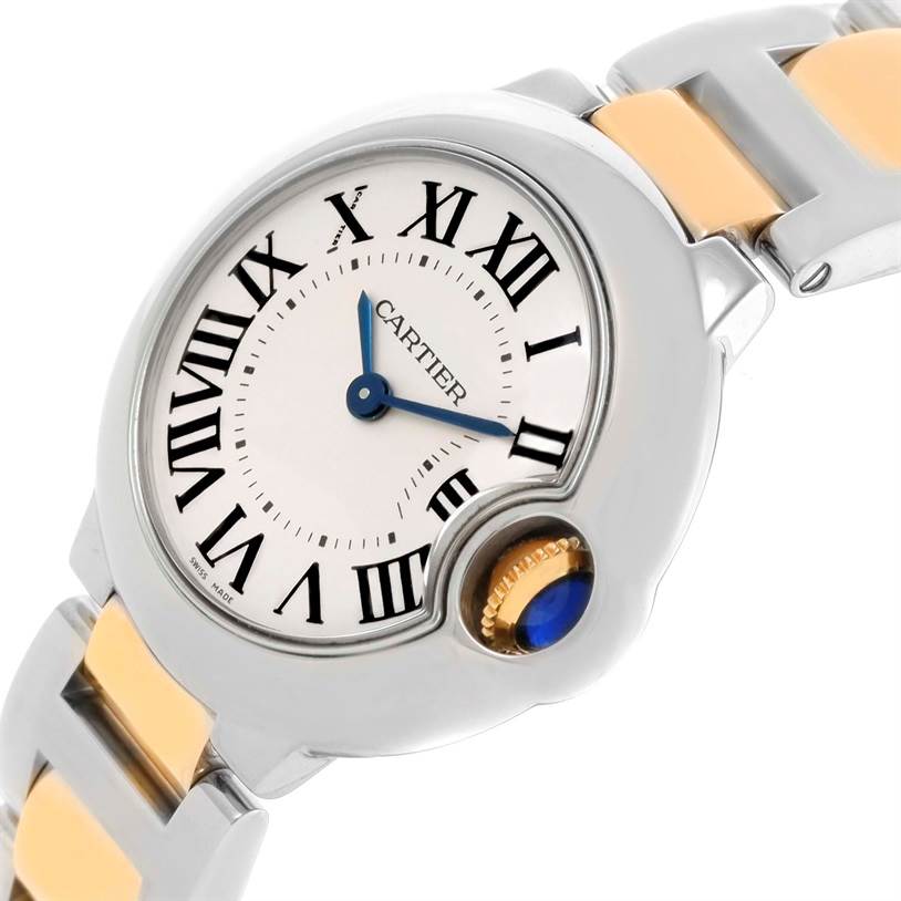 The image shows a close-up of the Cartier Ballon Bleu W69007Z3 Women
s Stainless Steel Silver Dial W69007Z3 Women
s Stainless Steel Silver Dial watch dial and crown, focusing on the Roman numerals and blue hands.