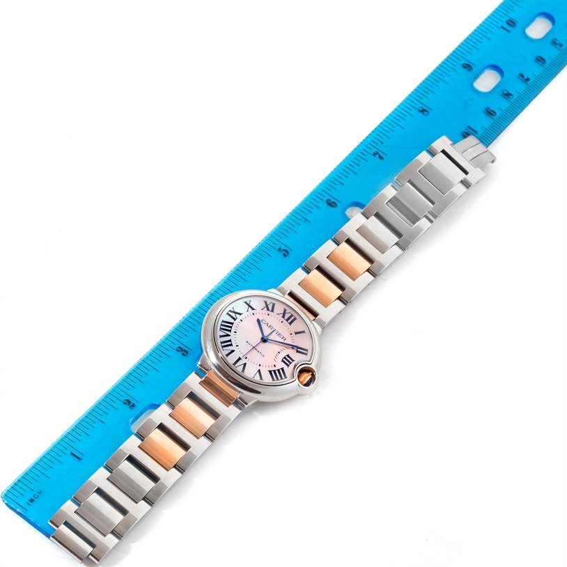 The image shows a Cartier Ballon Bleu W6920070 Women's Steel and Gold (two tone) Mother of Pearl Dial W6920070 Women's Steel and Gold (two tone) Mother of Pearl Dial watch laid flat with a ruler for size reference.