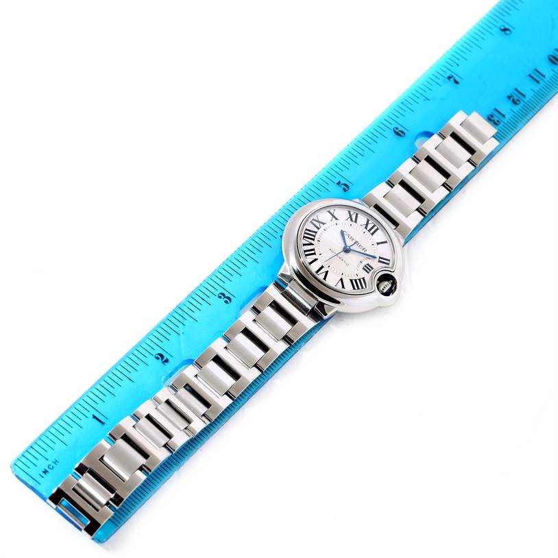 The Cartier Ballon Bleu W6920071 Women
s Stainless Steel Silver Dial W6920071 Women
s Stainless Steel Silver Dial watch is shown from a top-down angle next to a blue ruler, displaying the dial and bracelet.