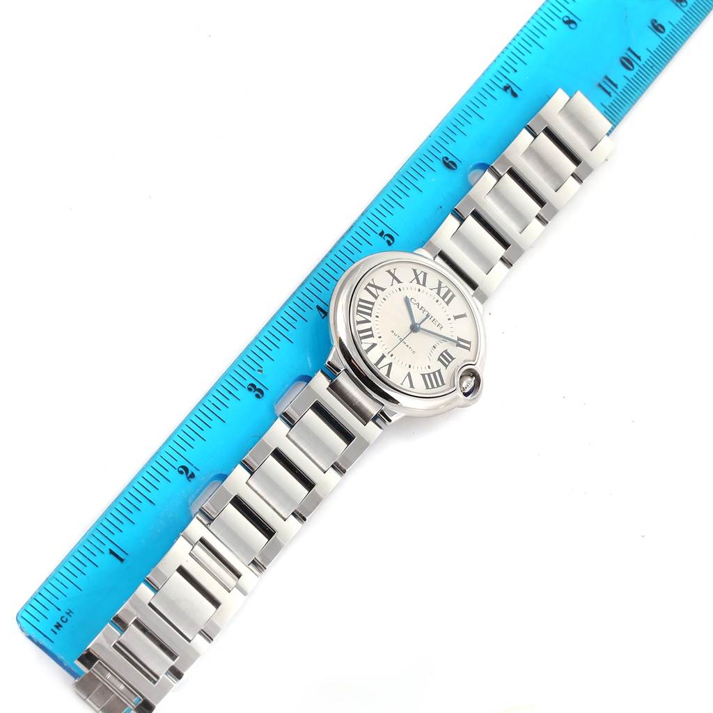 The image shows a Ballon Bleu de Cartier watch placed next to a ruler, viewed from a top-down angle.