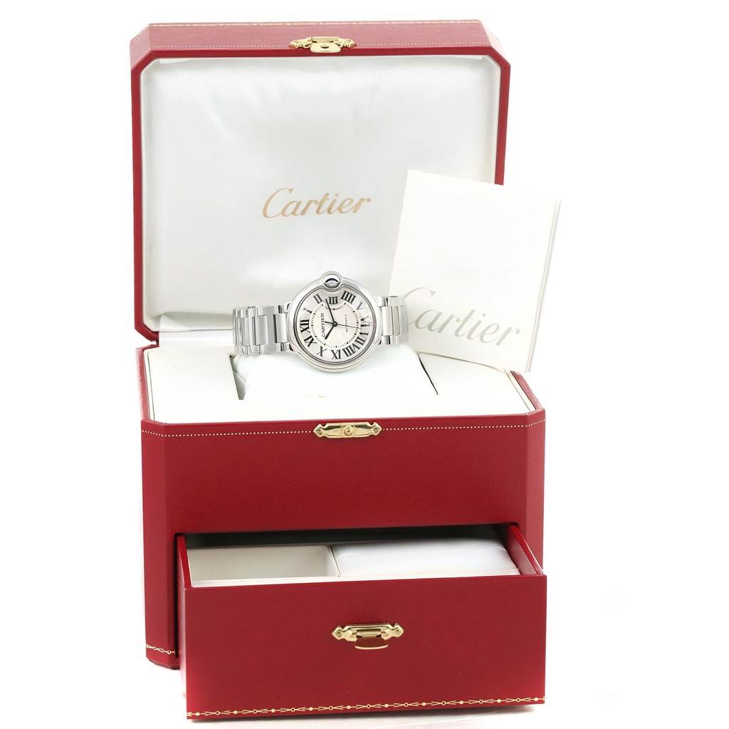 The image shows a Cartier Ballon Bleu W6920046 Women
s Stainless Steel Silver Dial W6920046 Women
s Stainless Steel Silver Dial watch from a front angle, inside an open red box with a drawer, alongside accompanying documentation.