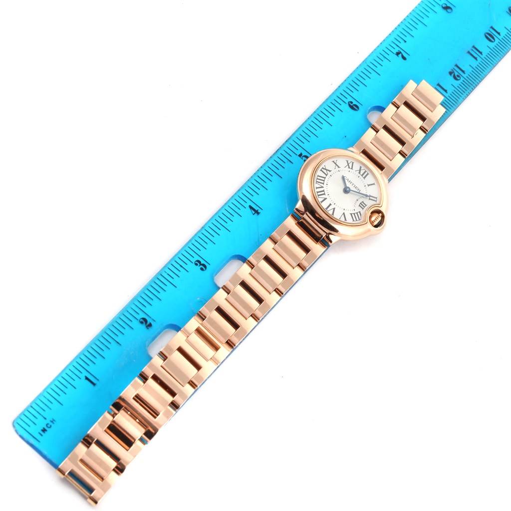 The image shows a Cartier Ballon Bleu W69002Z2 Women
s Rose Gold Silver Dial W69002Z2 Women
s Rose Gold Silver Dial watch laid flat next to a blue ruler, highlighting its bracelet and face.