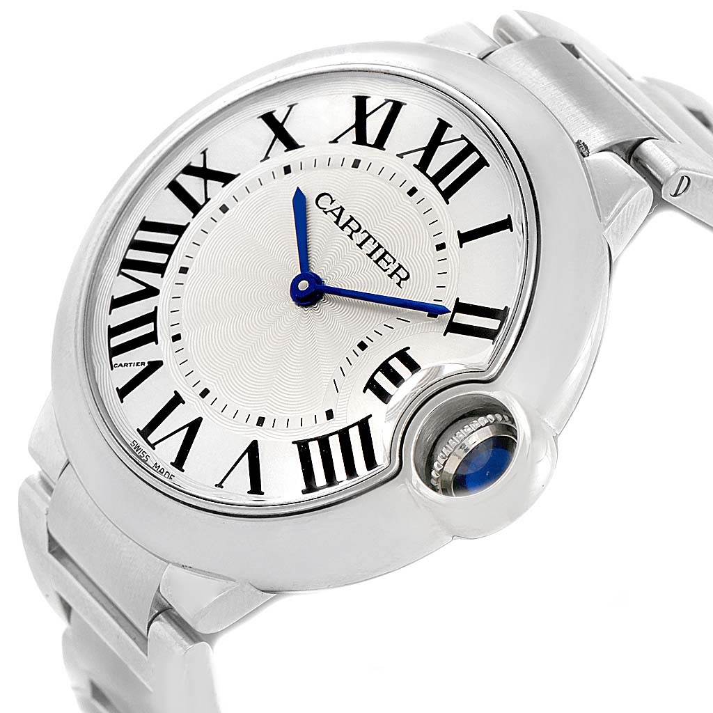 The image shows a tilted angle of the Ballon Bleu model by Cartier, highlighting its Roman numerals, blue hands, and metal bracelet.
