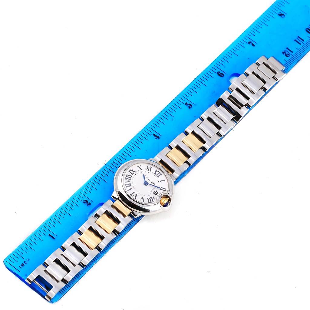 The image shows the entire Ballon Bleu watch by Cartier laid flat next to a blue ruler.