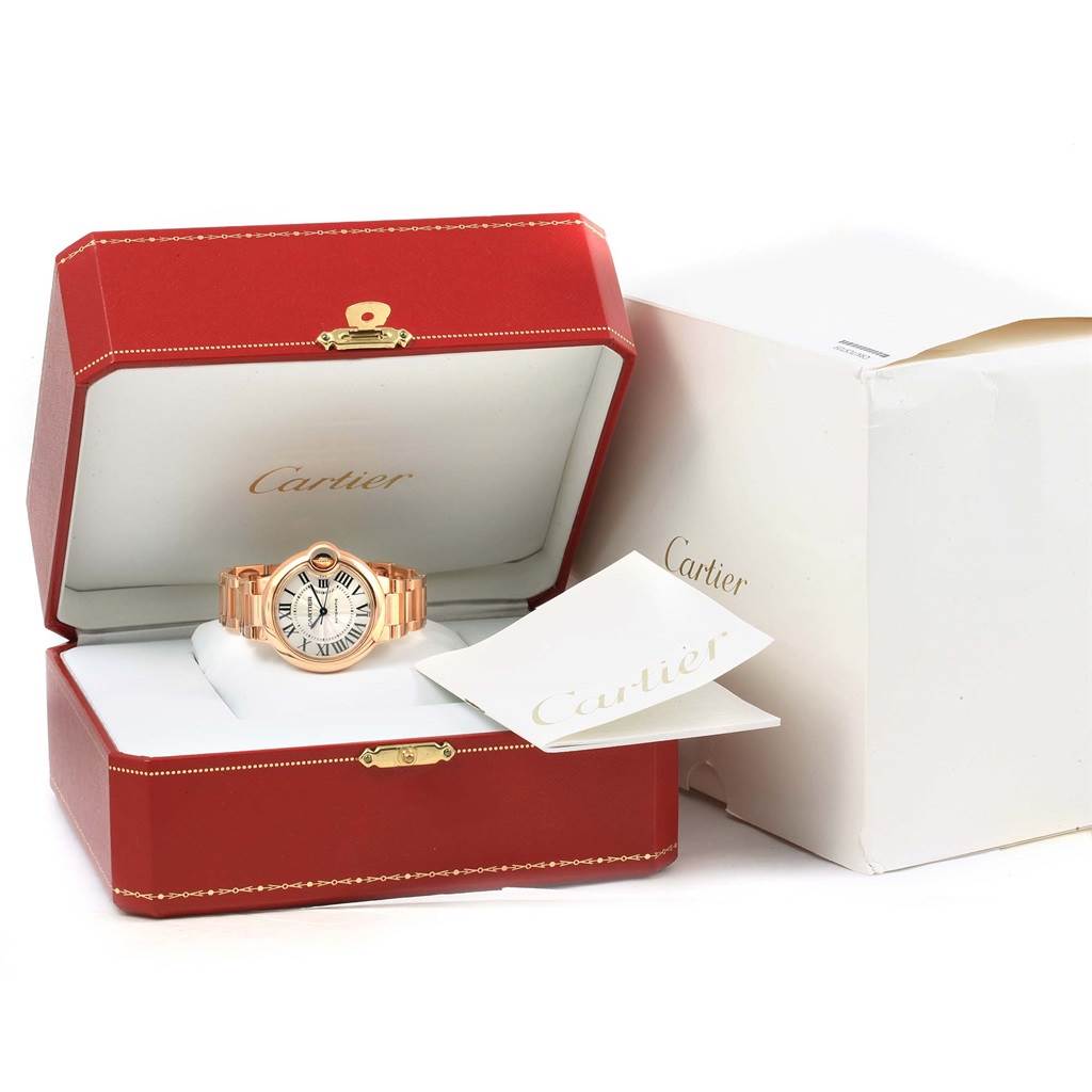 The Ballon Bleu de Cartier watch is displayed in an open red Cartier box with paperwork beside it.