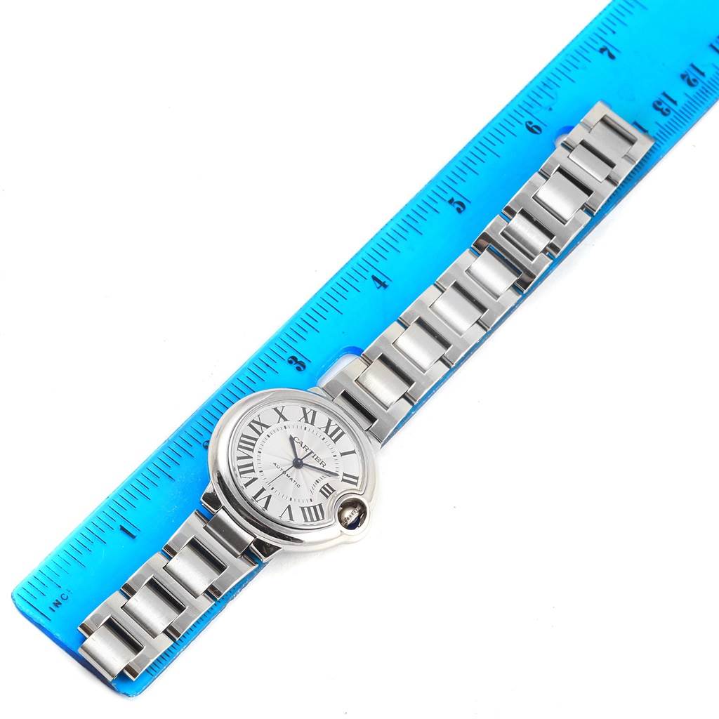 The watch shown is a Cartier Ballon Bleu W6920071 Women
s Stainless Steel Silver Dial W6920071 Women
s Stainless Steel Silver Dial model, displayed flat with its entire bracelet and face visible alongside a blue ruler for scale.