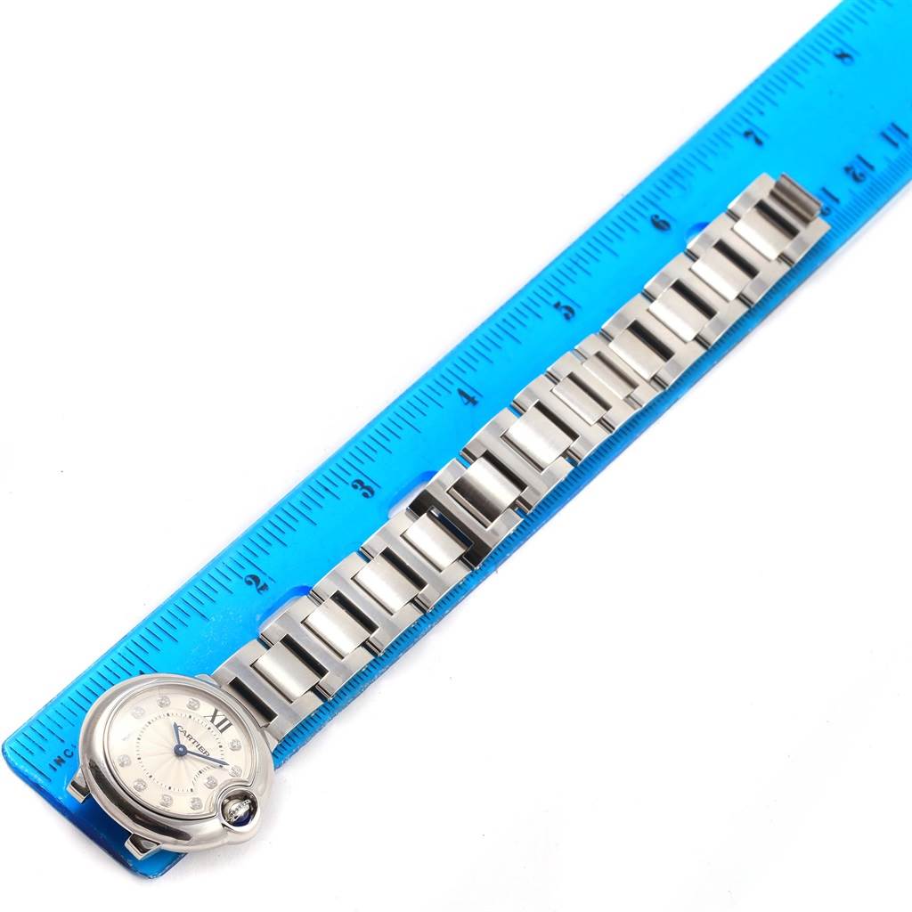 The image shows a top-down view of a Cartier Ballon Bleu WE902073 Women
s Stainless Steel Silver Dial WE902073 Women
s Stainless Steel Silver Dial watch placed next to a blue ruler for measurement.