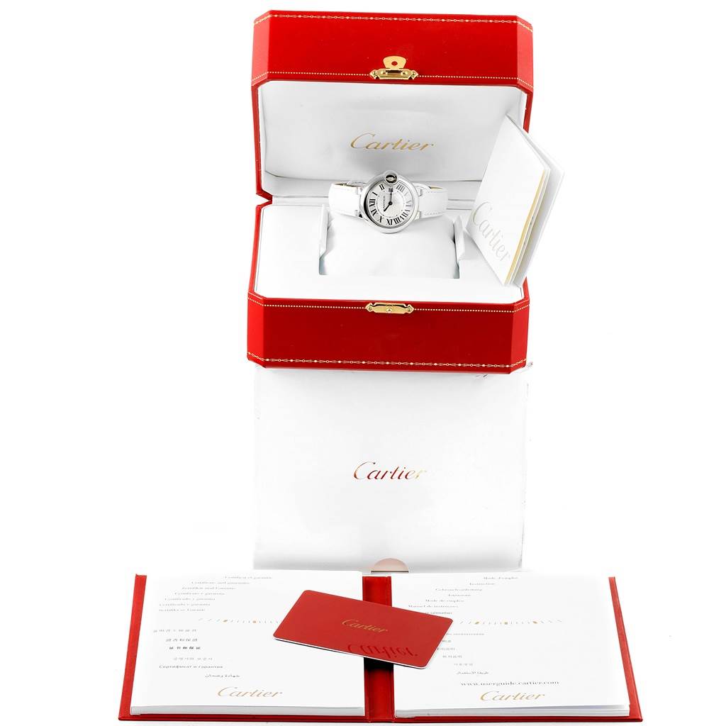 The image shows the Ballon Bleu model by Cartier in its open red box, accompanied by booklets and a authenticity card.