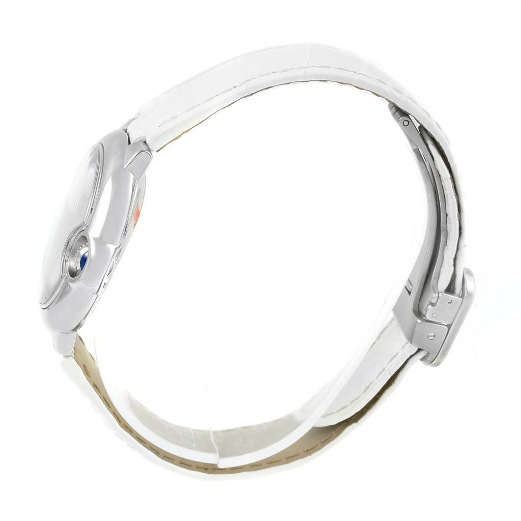 The image shows a side view of the Cartier Ballon Bleu W6920086 Women's Stainless Steel Silver Dial W6920086 Women's Stainless Steel Silver Dial watch, highlighting its case, crown, and white leather strap.