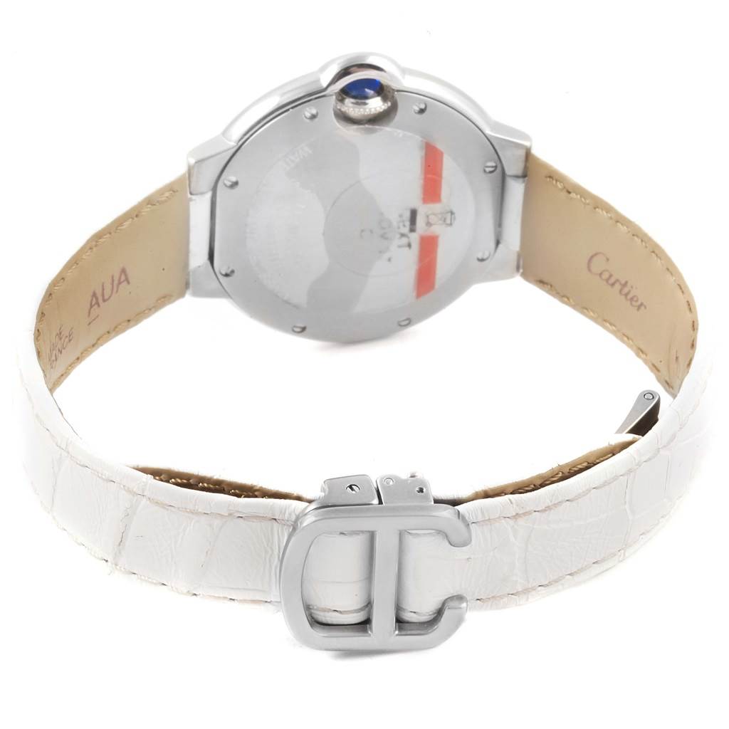 The image shows the back of a Ballon Bleu model by Cartier, focusing on the case back, crown, and white leather strap.