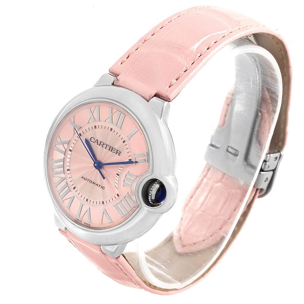 The image shows a Cartier Ballon Bleu WSBB0007 Women
s Stainless Steel Pink Dial WSBB0007 Women
s Stainless Steel Pink Dial watch at a three-quarter angle, showcasing its pink dial, Roman numeral indices, and pink leather strap.