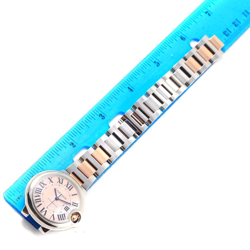 The Ballon Bleu model by Cartier is shown from above, featuring the watch face, bracelet, and part of a ruler for scale.