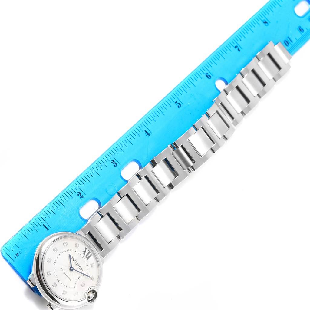 The image shows the face and metal bracelet of a Cartier Ballon Bleu WE902075 Women
s Stainless Steel Silver Dial WE902075 Women
s Stainless Steel Silver Dial watch, alongside a blue measuring ruler.