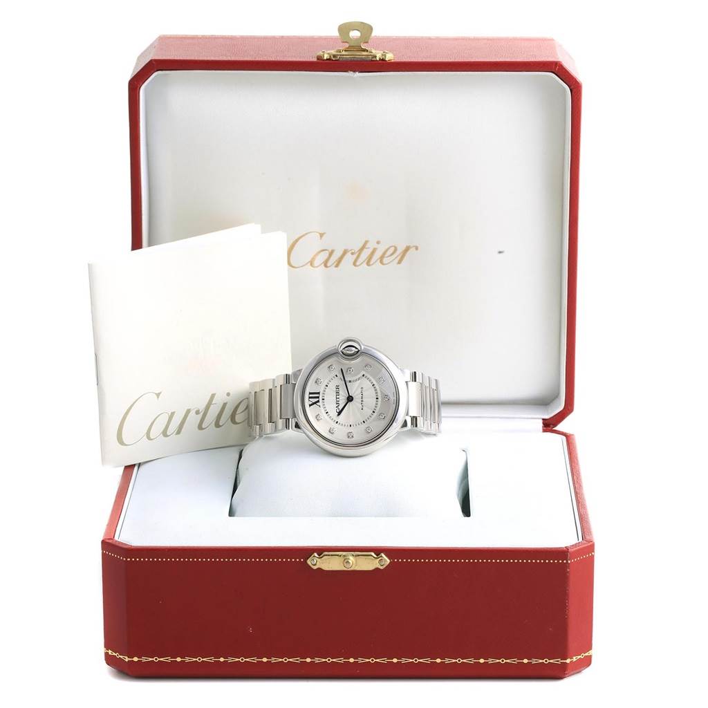 The Ballon Bleu de Cartier watch is shown front-facing, resting in its open Cartier box with associated booklets visible.