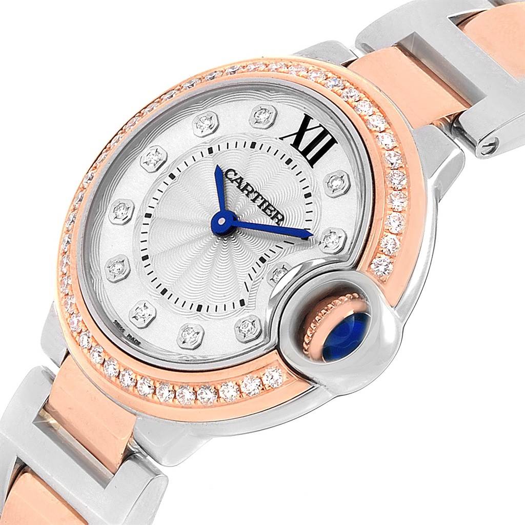This image shows a close-up, angled view of the Cartier Ballon Bleu WE902076 Women
s Steel and Gold (two tone) Silver Dial WE902076 Women
s Steel and Gold (two tone) Silver Dial watch, highlighting its face, crown, diamonds, and part of its metal bracelet.