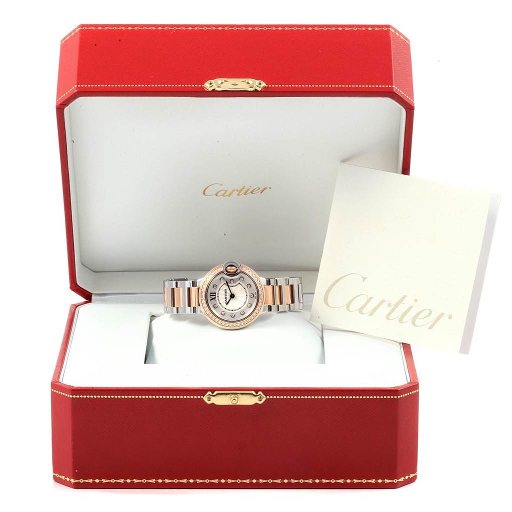 The Cartier Ballon Bleu WE902076 Women
s Steel and Gold (two tone) Silver Dial WE902076 Women
s Steel and Gold (two tone) Silver Dial watch is displayed front-on inside its red box, with a booklet to the side.
