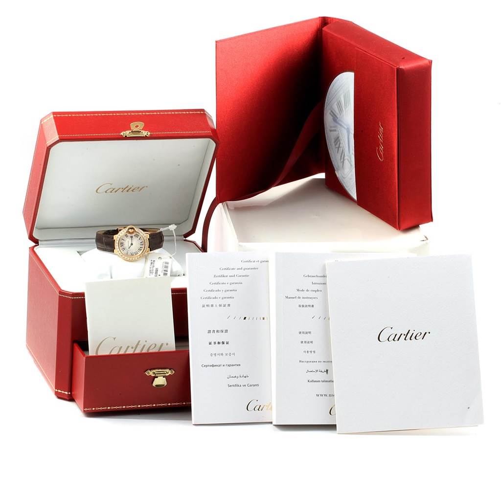 The image shows a Ballon Bleu by Cartier watch in its open box, along with accompanying booklets and documentation.