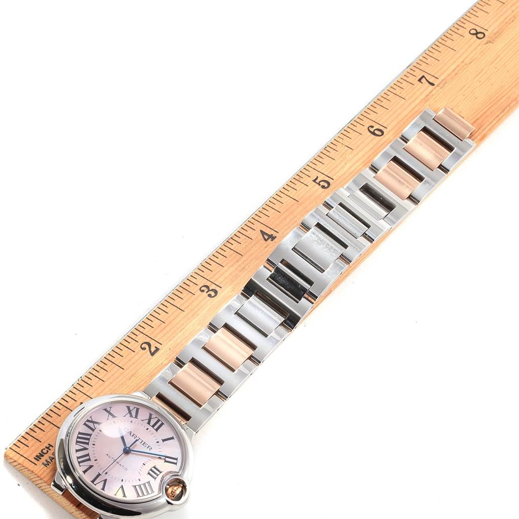 The image shows the Ballon Bleu model by Cartier laid flat next to a ruler, showing the watch face and the entire band.