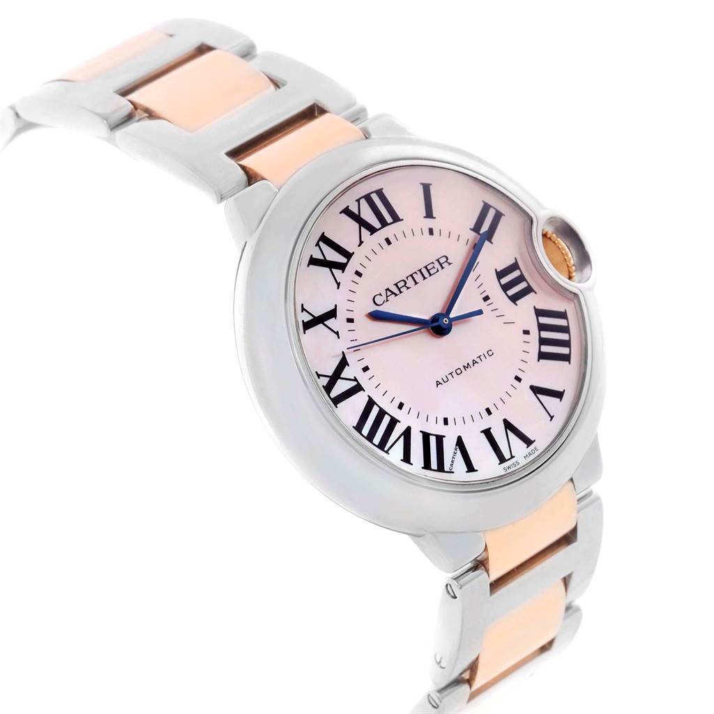 This image shows a side angle of the Cartier Ballon Bleu W6920070 Women's Steel and Gold (two tone) Mother of Pearl Dial W6920070 Women's Steel and Gold (two tone) Mother of Pearl Dial watch, highlighting its pink dial, Roman numerals, and two-tone metal bracelet.