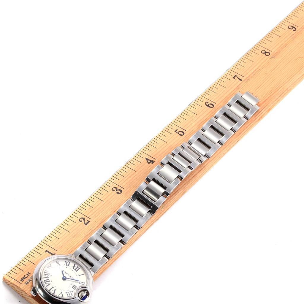 The image shows the Ballon Bleu model by Cartier laid flat next to a ruler, displaying its bracelet and part of the watch face.