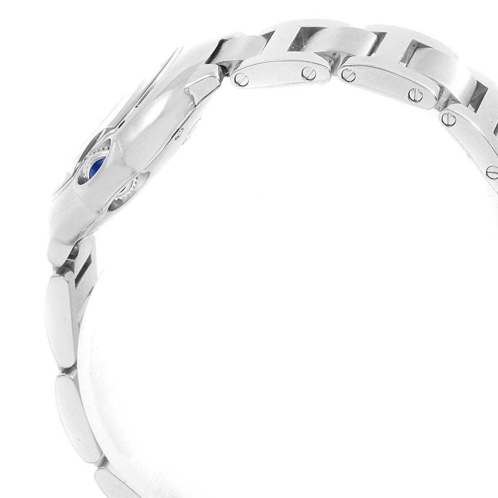 The image shows a side view of the Ballon Bleu watch by Cartier, highlighting its metal bracelet and crown with a blue cabochon.