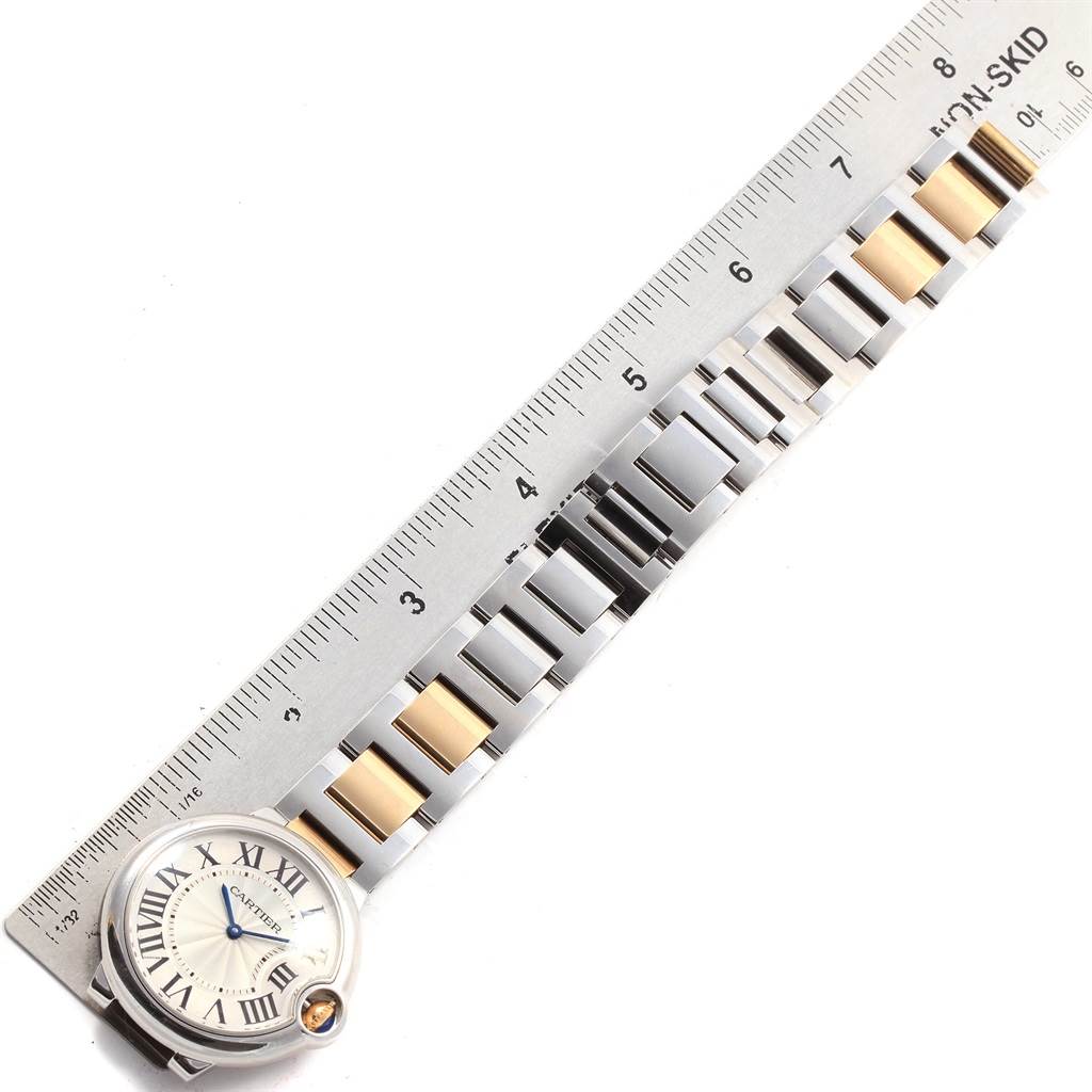 The image shows the face and part of the bracelet of a Cartier Ballon Bleu W69008Z3 Men
s Steel and Gold (two tone) Silver Dial W69008Z3 Men
s Steel and Gold (two tone) Silver Dial watch, alongside a measuring ruler.