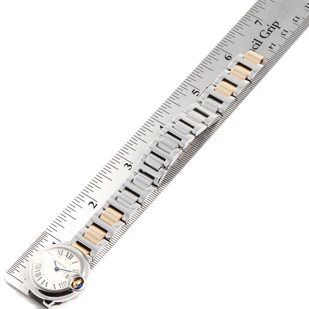 The Ballon Bleu model by Cartier is shown from an overhead angle, displaying the watch face and band alongside a ruler.