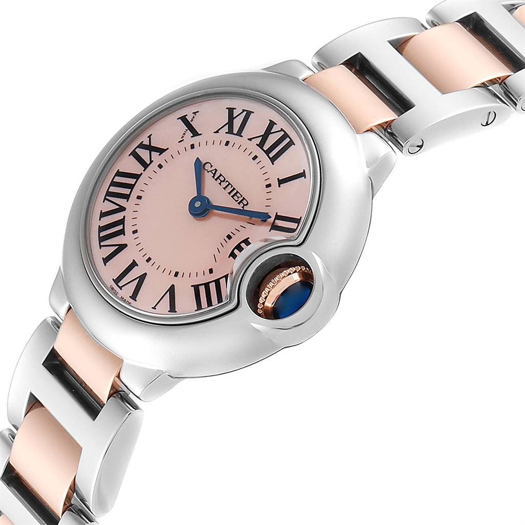 The Ballon Bleu de Cartier watch is shown at an angled view, highlighting its dial, Roman numerals, crown, and metal bracelet.