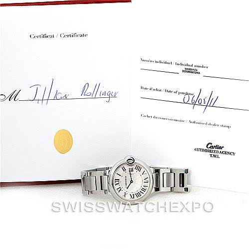 The image shows a Cartier Ballon Bleu W69011Z4 Women
s Stainless Steel Silver Dial W69011Z4 Women
s Stainless Steel Silver Dial watch placed in front of its accompanying warranty or certificate documents.