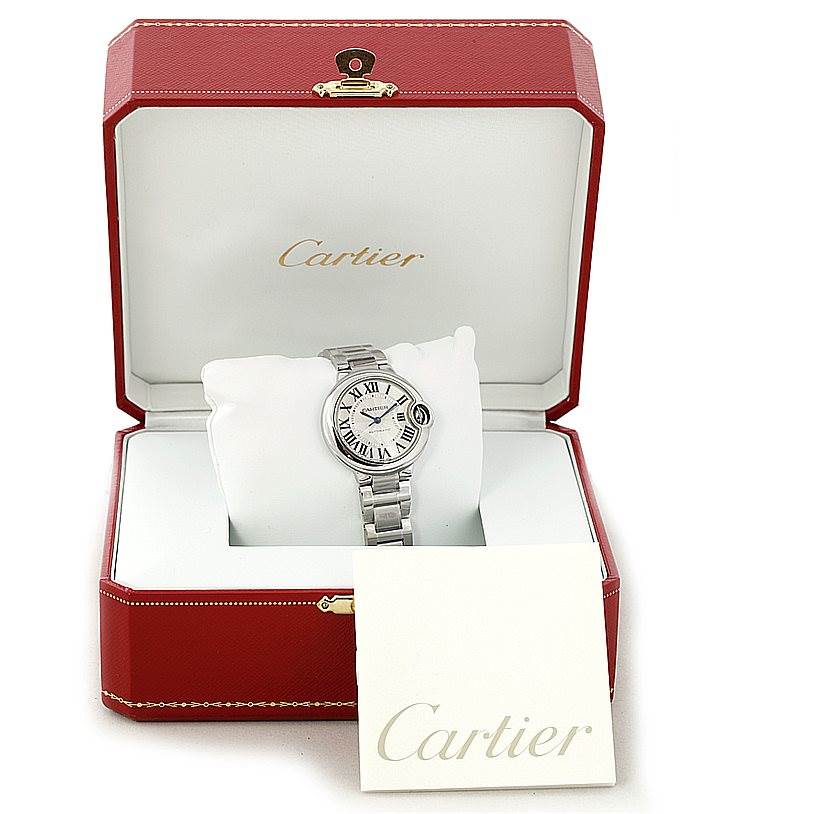 The Cartier Ballon Bleu W6920046 Women's Stainless Steel Silver Dial W6920046 Women's Stainless Steel Silver Dial watch is shown front-facing inside an open red Cartier box with a Cartier booklet beside it.