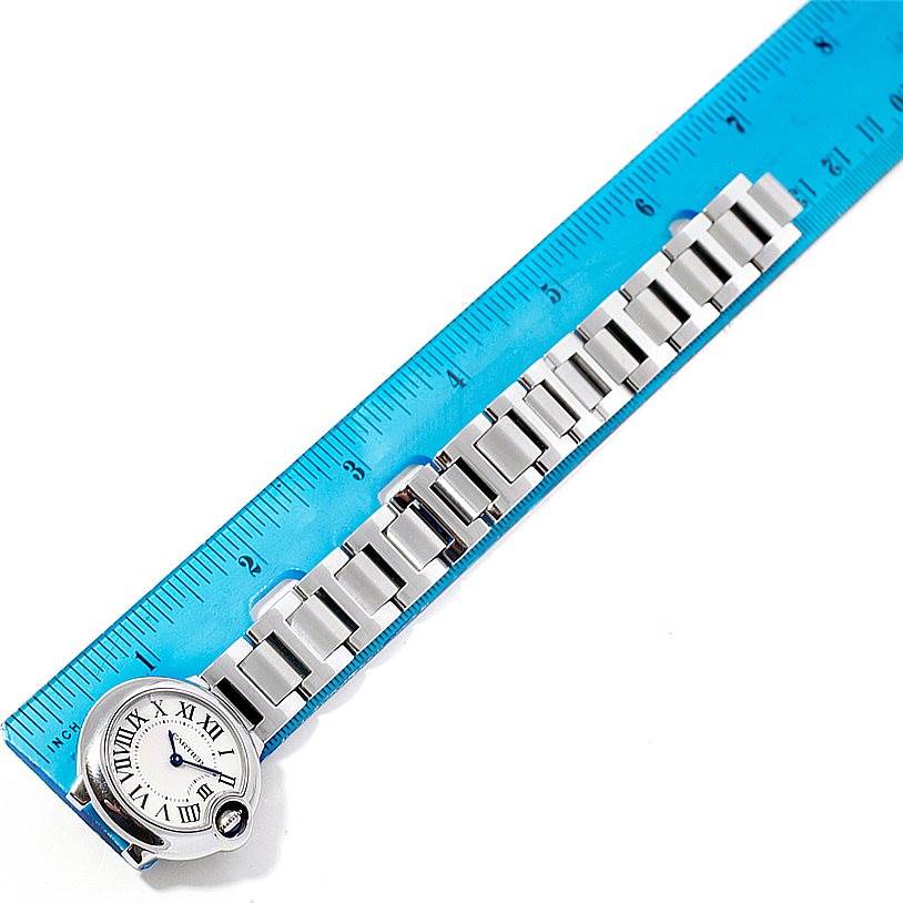 The image shows a top view of a Ballon Bleu de Cartier watch alongside a blue ruler.