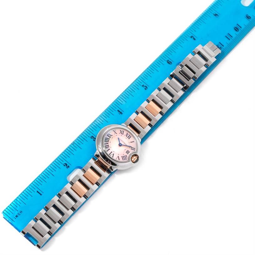 The image shows the front view of a Cartier Ballon Bleu W69011Z4 Women's Steel and Gold (two tone) Mother of Pearl Dial W69011Z4 Women's Steel and Gold (two tone) Mother of Pearl Dial watch laid next to a blue ruler for scale.