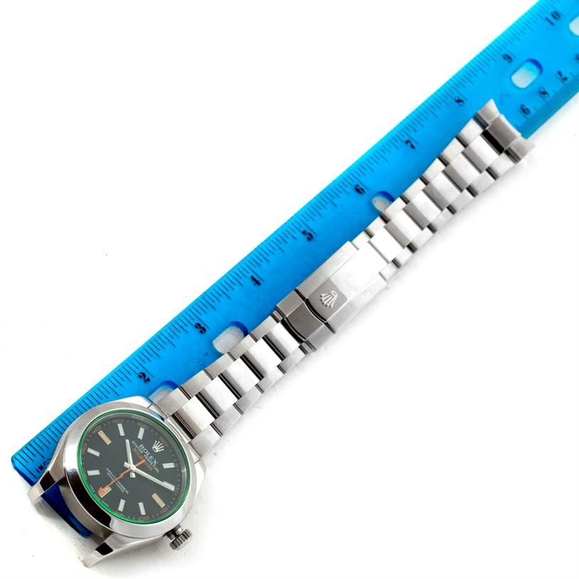 The image shows a Rolex Milgauss 116400V Men's Stainless Steel Black Dial 116400V Men's Stainless Steel Black Dial watch laid flat, alongside a blue ruler measuring its stainless steel bracelet and clasp.
