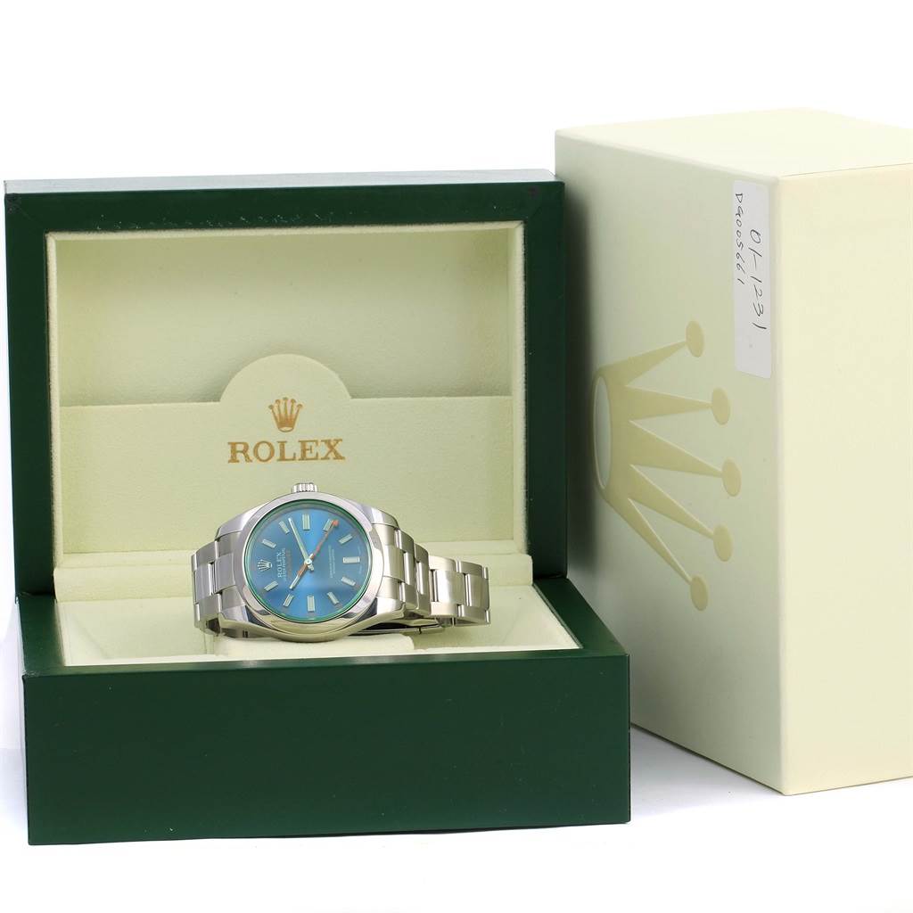 The Rolex Milgauss 116400GV Men's Stainless Steel Blue Dial 116400GV Men's Stainless Steel Blue Dial watch is displayed at a slightly downward angle within its green and beige box, next to the outer box.