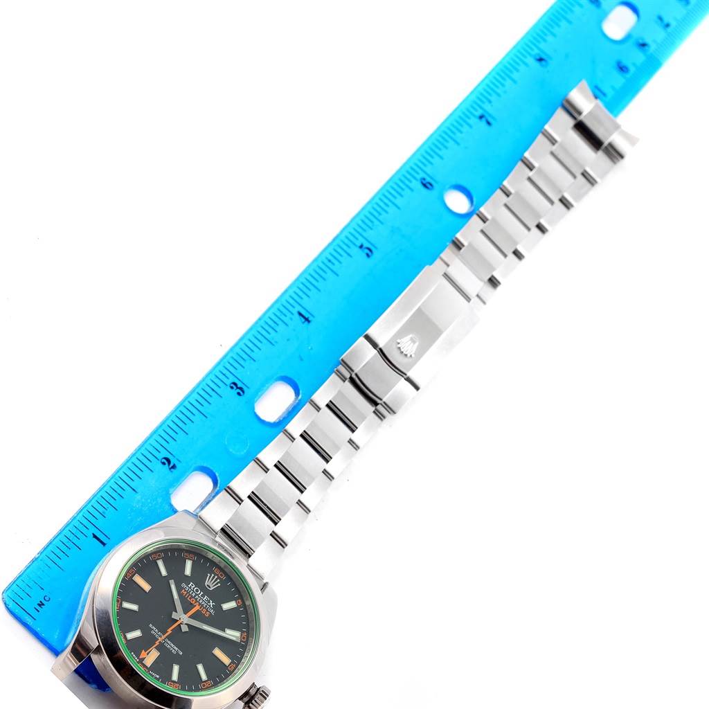 The image shows the Rolex Milgauss 116400V Men's Stainless Steel Black Dial 116400V Men's Stainless Steel Black Dial watch laid flat next to a ruler, displaying the watch face and stainless steel bracelet.