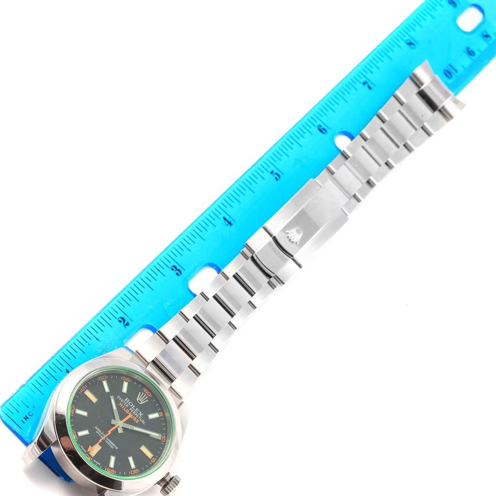 This image shows the Rolex Milgauss 116400V Men's Stainless Steel Black Dial 116400V Men's Stainless Steel Black Dial watch horizontally aligned with a blue ruler, displaying the face and metal bracelet.