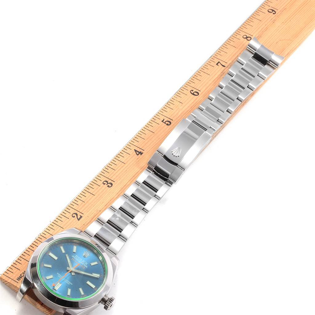 The Rolex Milgauss 116400 Men's Stainless Steel Blue Dial 116400 Men's Stainless Steel Blue Dial watch is displayed flat against a ruler, showing its face, bracelet, and clasp.