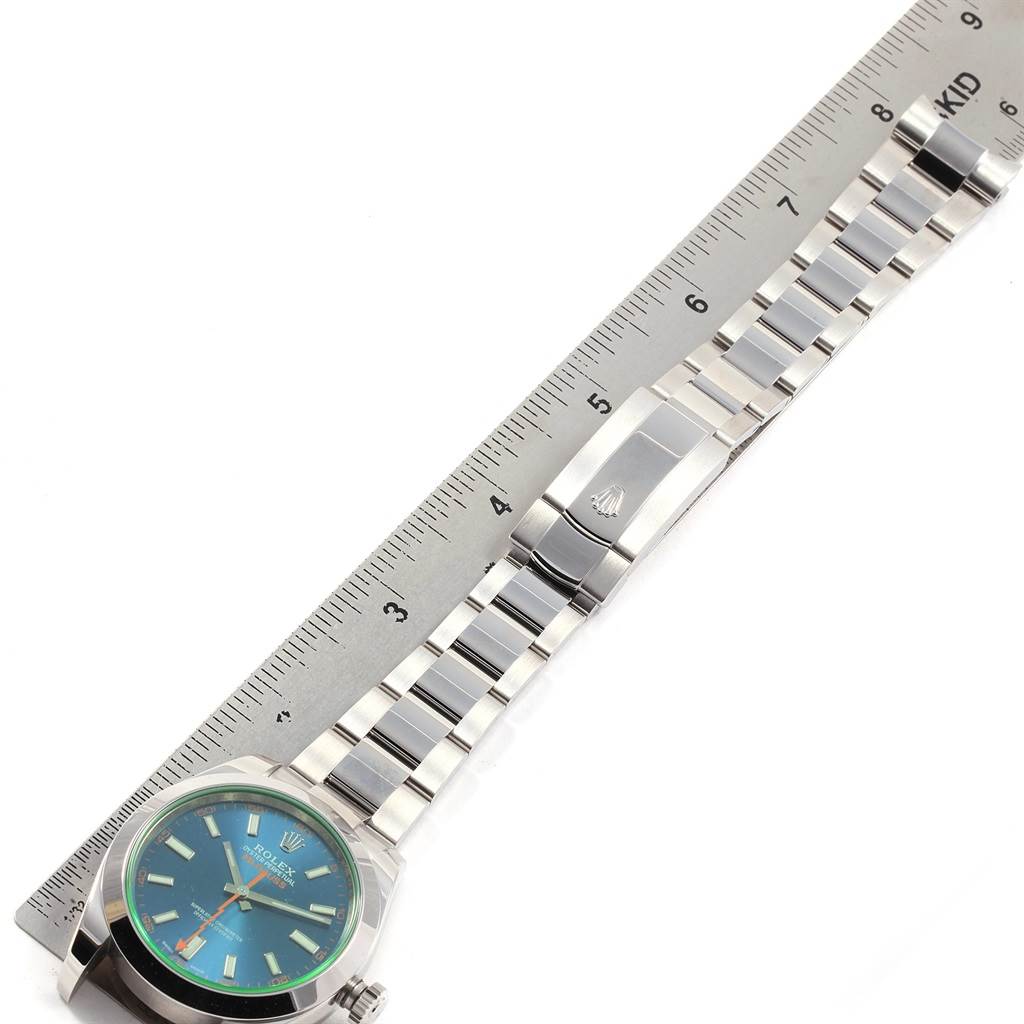 The Rolex Milgauss 116400GV Men's Stainless Steel Blue Dial 116400GV Men's Stainless Steel Blue Dial watch is shown laying flat with its face, bracelet, and clasp visible next to a ruler for scale.