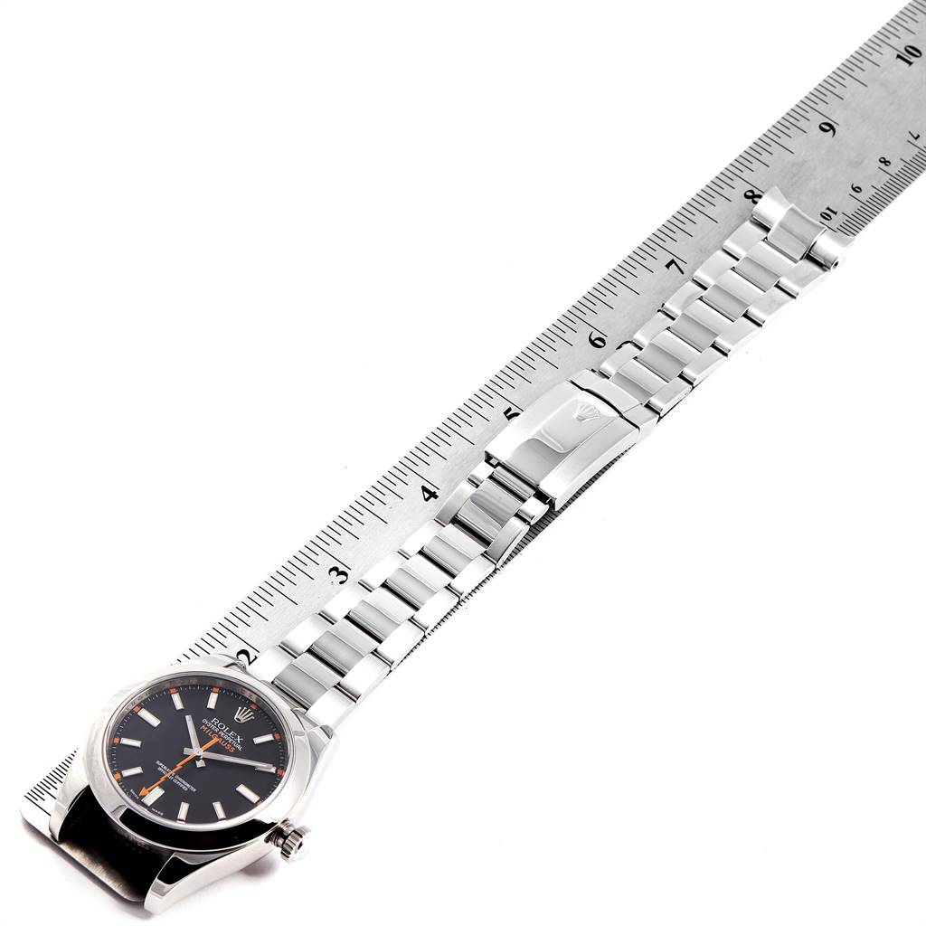 The image shows a Rolex Milgauss 116400 Men's Stainless Steel Black Dial 116400 Men's Stainless Steel Black Dial watch laying flat with its face and bracelet fully extended next to a ruler.