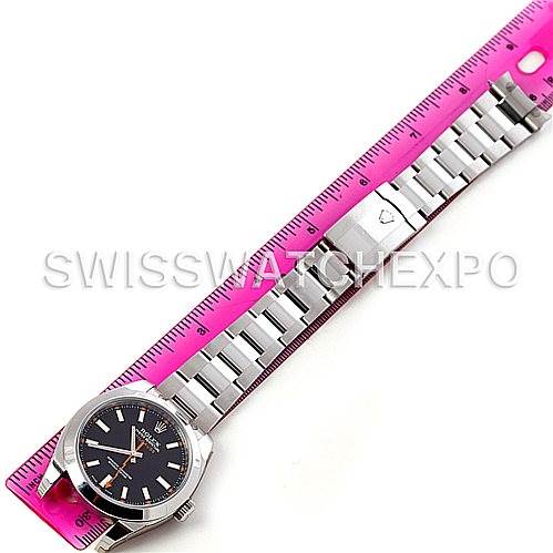 The Rolex Milgauss 116400BKSO Men's Stainless Steel Black Dial 116400BKSO Men's Stainless Steel Black Dial watch is shown fully extended with a pink measuring ruler underneath, capturing the watch dial and stainless steel bracelet.