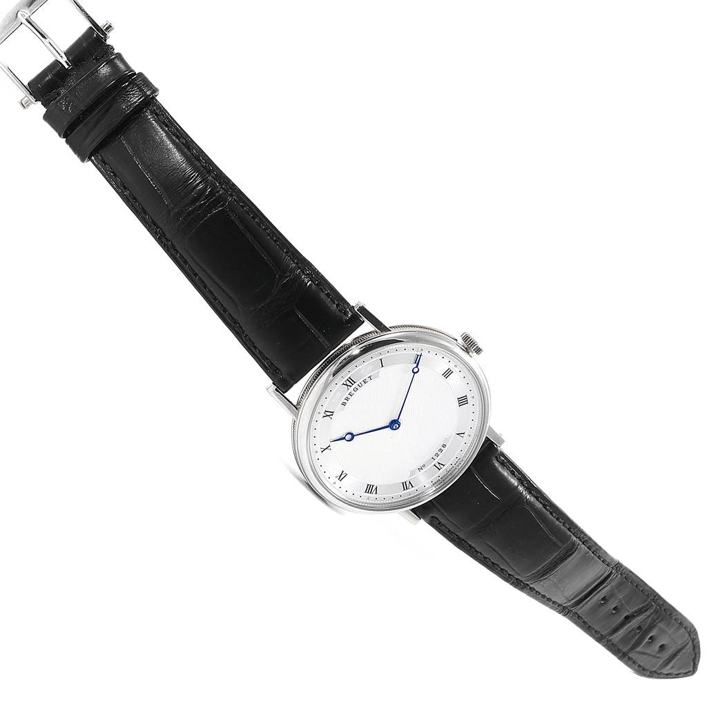 This image shows a Breguet Classique 5157BB/11/9V6 Men's White Gold Silver Dial 5157BB/11/9V6 Men's White Gold Silver Dial watch at an angled view, displaying its face, black leather strap, and blue hands.