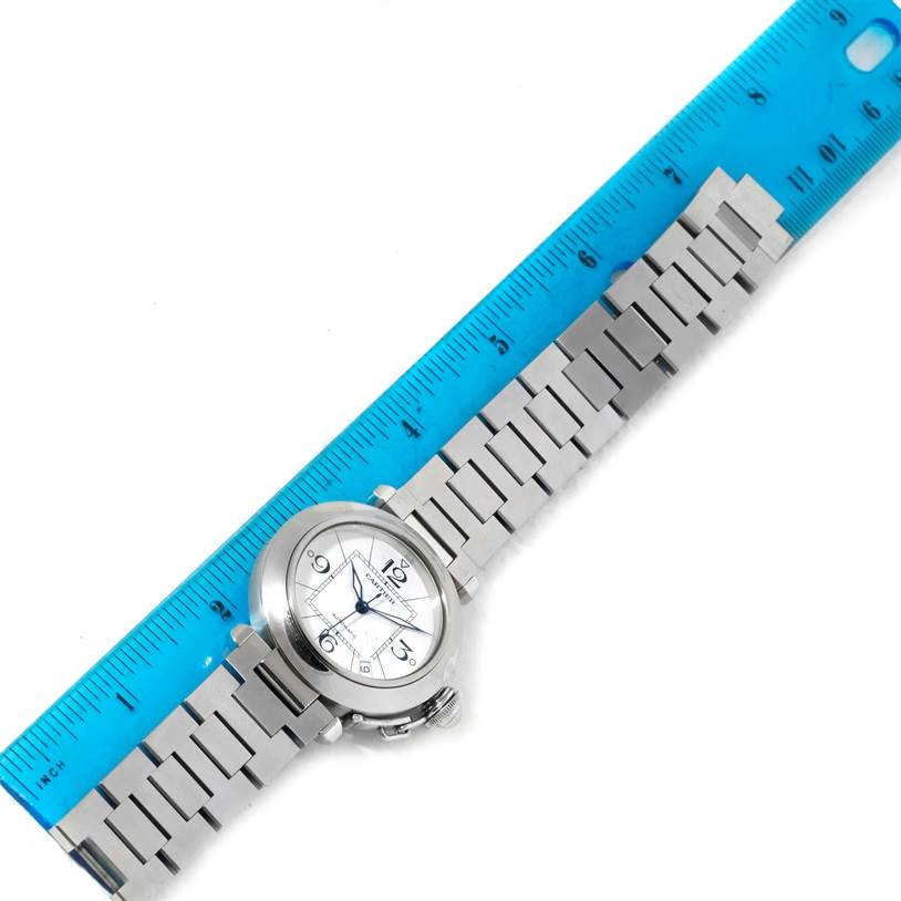 The image shows a Cartier Pasha W31074M7 Women's Stainless Steel White Dial W31074M7 Women's Stainless Steel White Dial watch lying flat next to a blue ruler for scale.