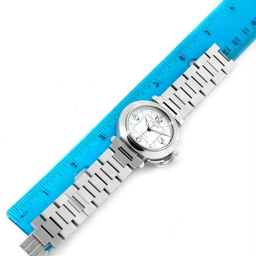 The Cartier Pasha W31074M7 Women's Stainless Steel White Dial W31074M7 Women's Stainless Steel White Dial watch is shown flat with a blue ruler for measurement, displaying its face and metal bracelet.