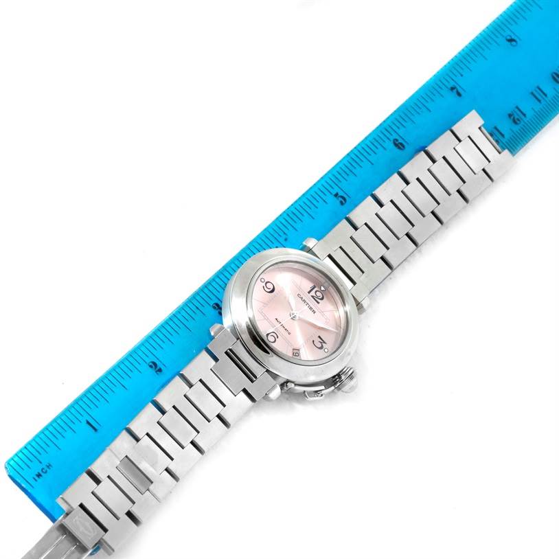 The Cartier Pasha W31075M7 Women
s Stainless Steel Pink Dial W31075M7 Women
s Stainless Steel Pink Dial watch is shown from a top-down angle, with the bracelet, dial, and part of a ruler visible.