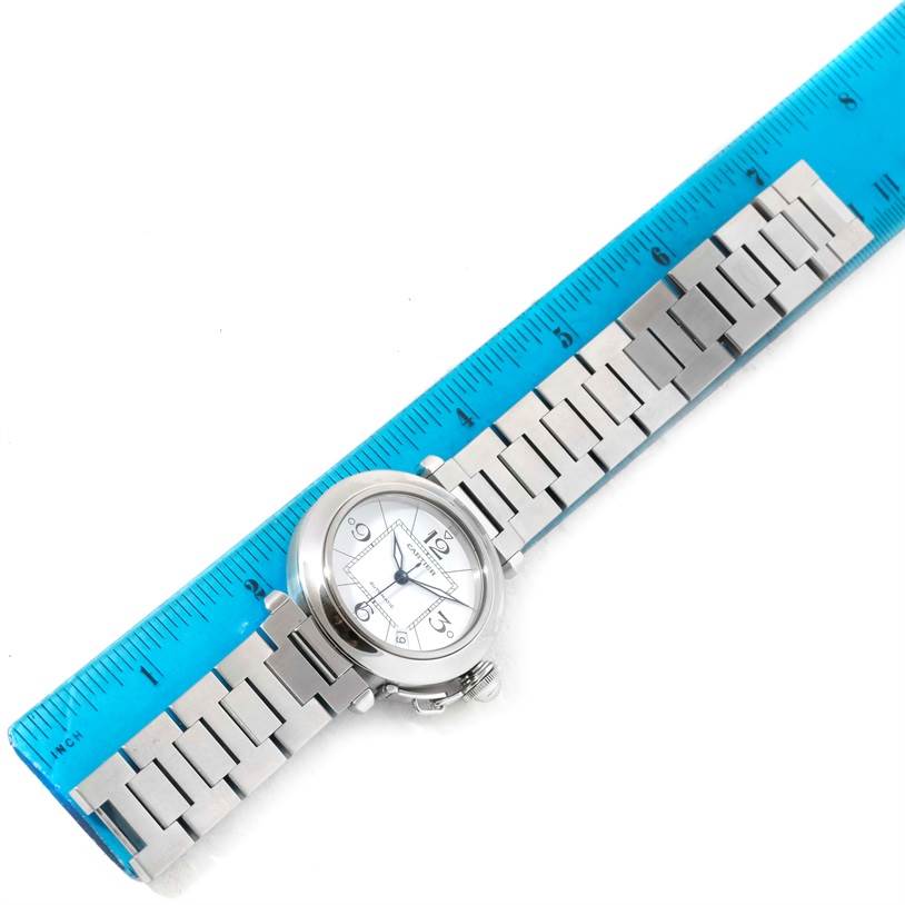 The image shows a Cartier Pasha W31074M7 Stainless Steel White Dial W31074M7 Stainless Steel White Dial watch lying flat beside a blue ruler, highlighting its face and metal bracelet.