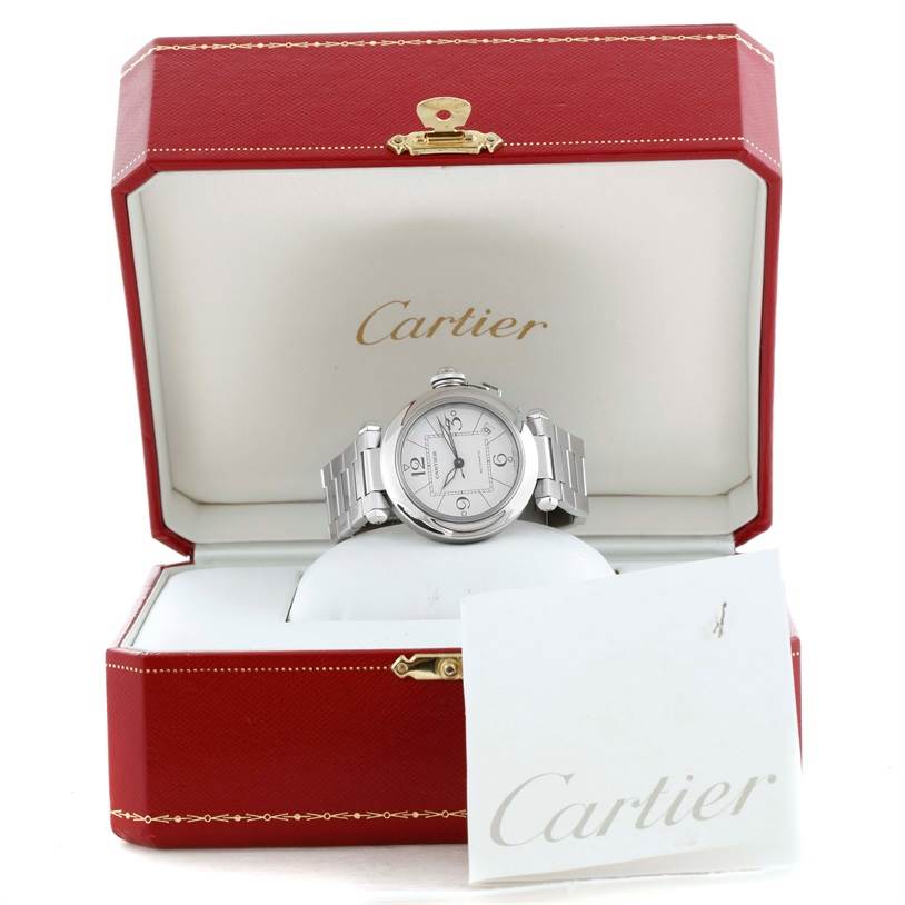 The Cartier Pasha W31074M7 Stainless Steel White Dial W31074M7 Stainless Steel White Dial watch is shown front-facing inside its red Cartier box, with a card displaying the brand
s logo.